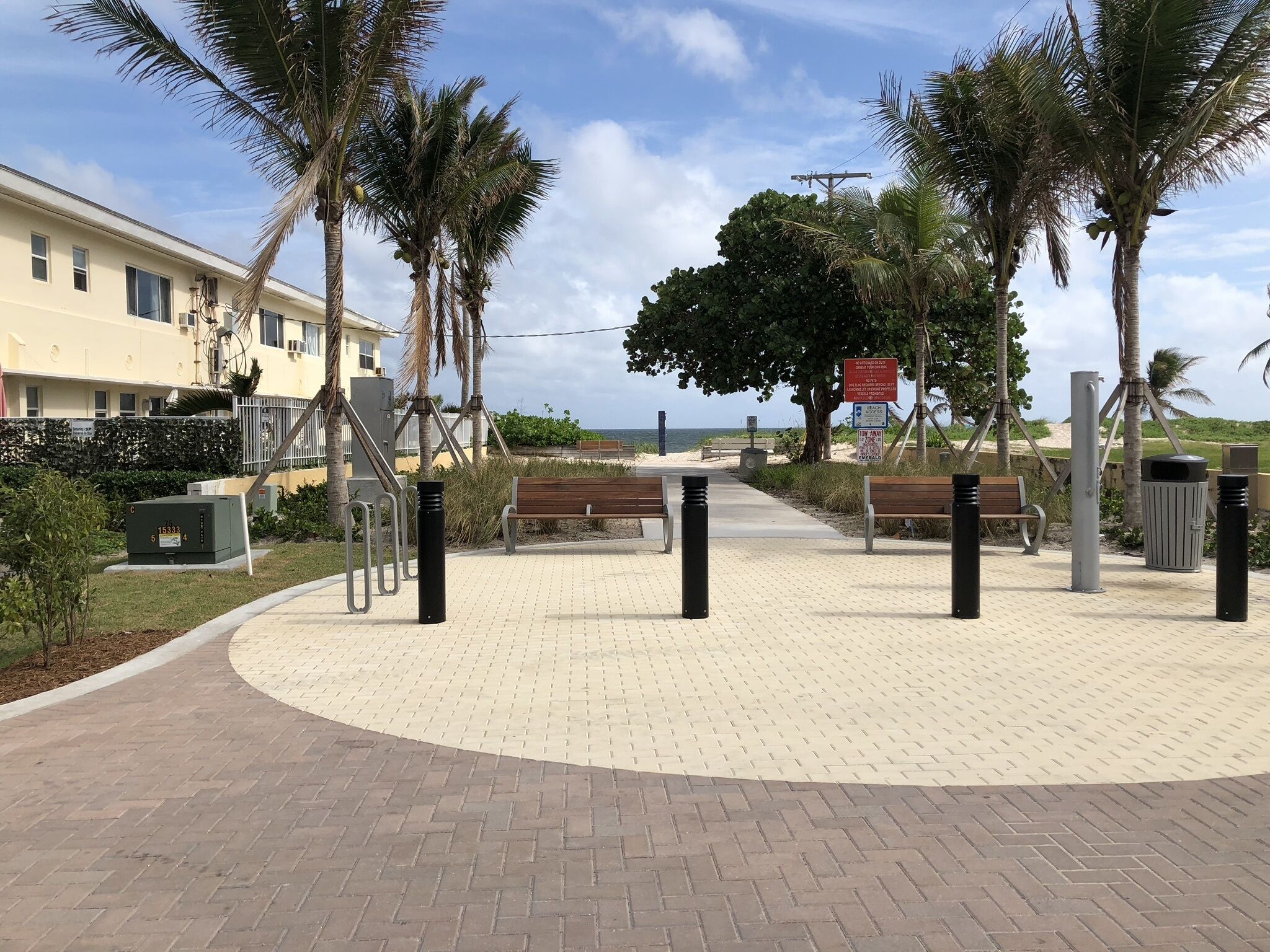 Une promenade dallée, agrémentée de bancs, de palmiers et offrant une vue sur l’océan.