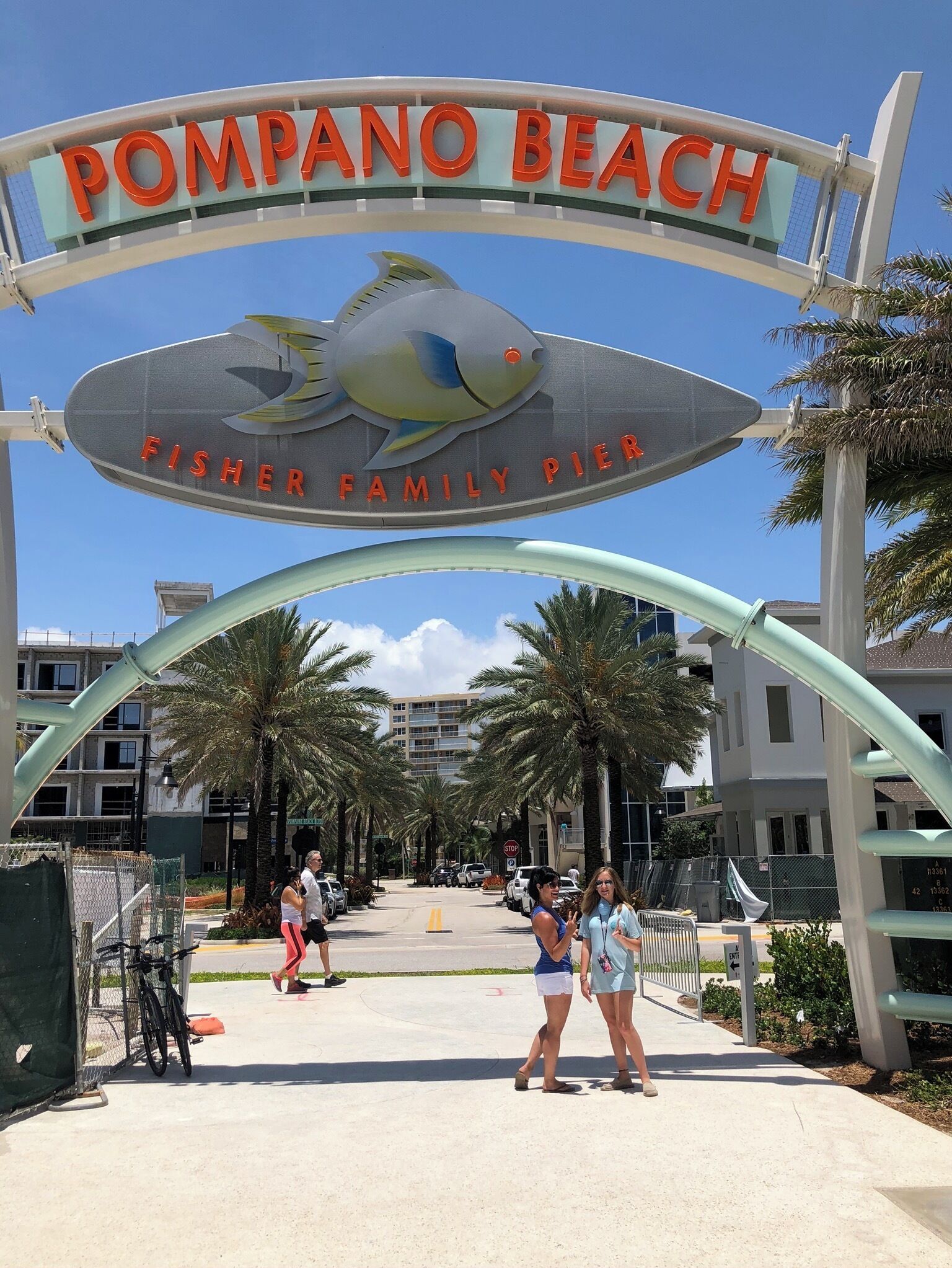 A sign for Pompano Beach Fisher Family Pier with a stylized fish design.