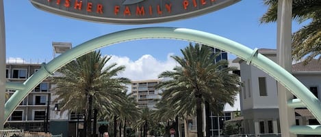A sign for Pompano Beach Fisher Family Pier with a stylized fish design.