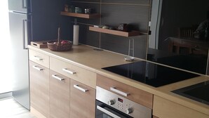 Eine moderne Küche mit Holzschränken, einem Einbauofen und einem schwarzen Kochfeld.
