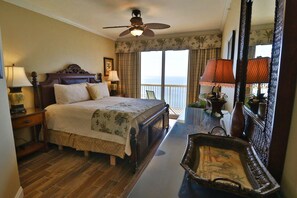 A hotel room with a large bed, a ceiling fan, a balcony with a view, and a decorative mirror.