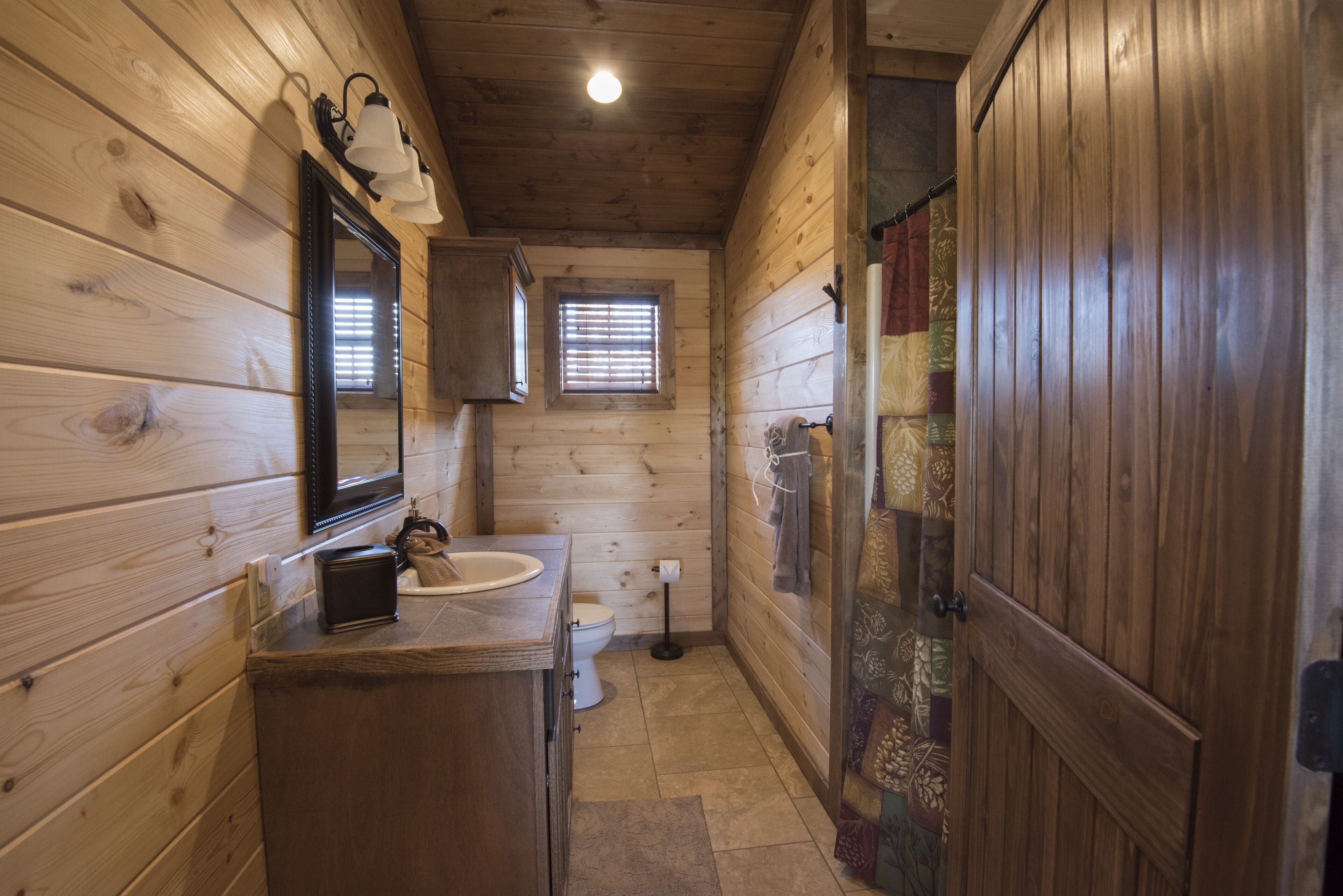 A wooden-paneled bathroom with a sink, mirror, and toilet.