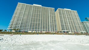 Un hotel de gran altura con varios pisos y balcones, ubicado en una playa de arena.