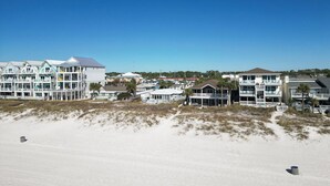 Un hotel sulla spiaggia con edifici a più piani, balconi e una spiaggia sabbiosa in primo piano.