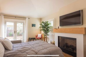 Relax in this serene bedroom with a large bed, TV, and cozy fireplace.