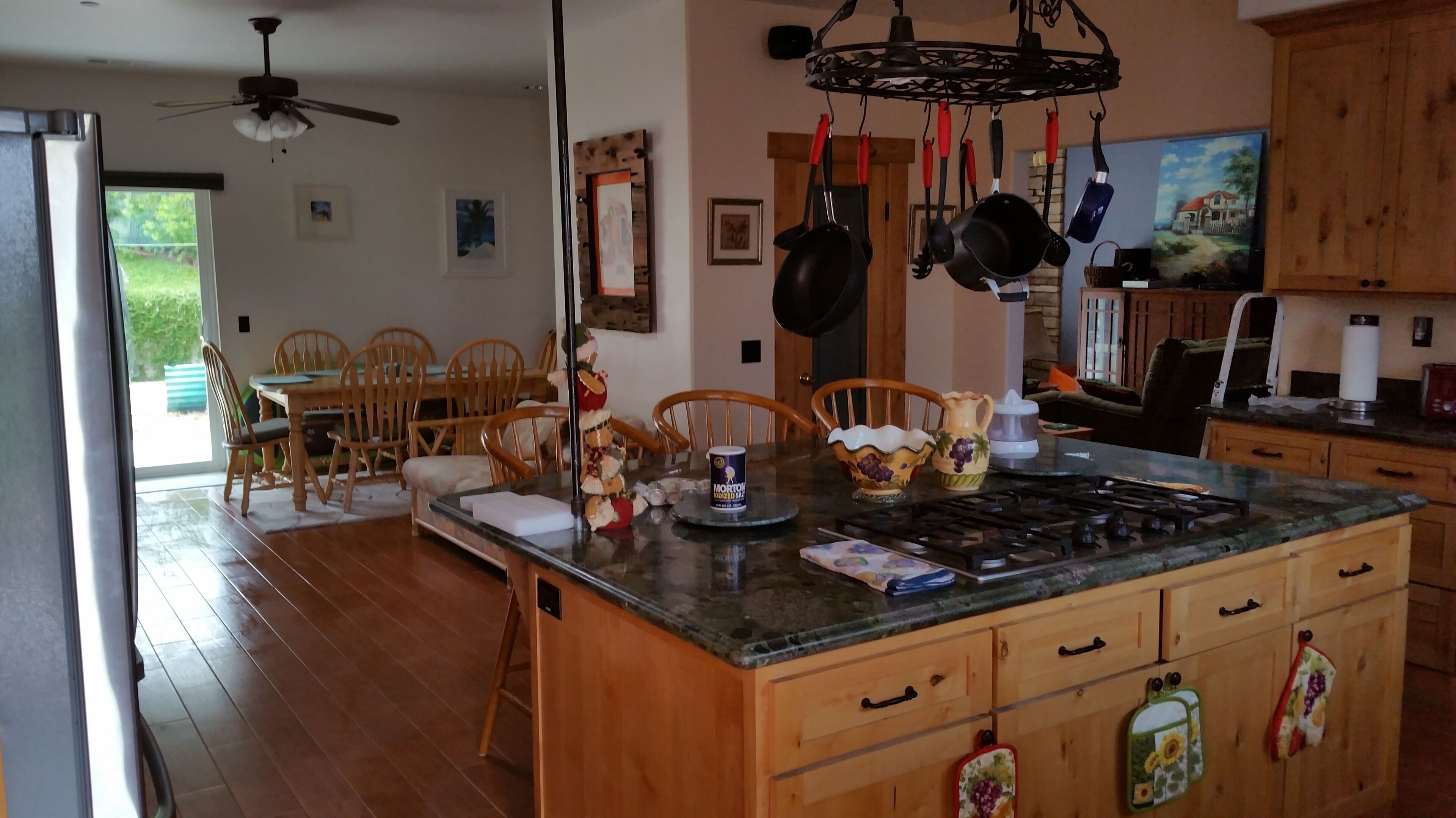 A kitchen with wooden cabinets, a central island, and a dining area with chairs.