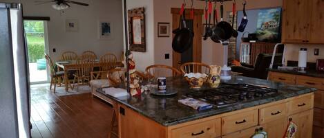 A kitchen with wooden cabinets, a central island, and a dining area with chairs.