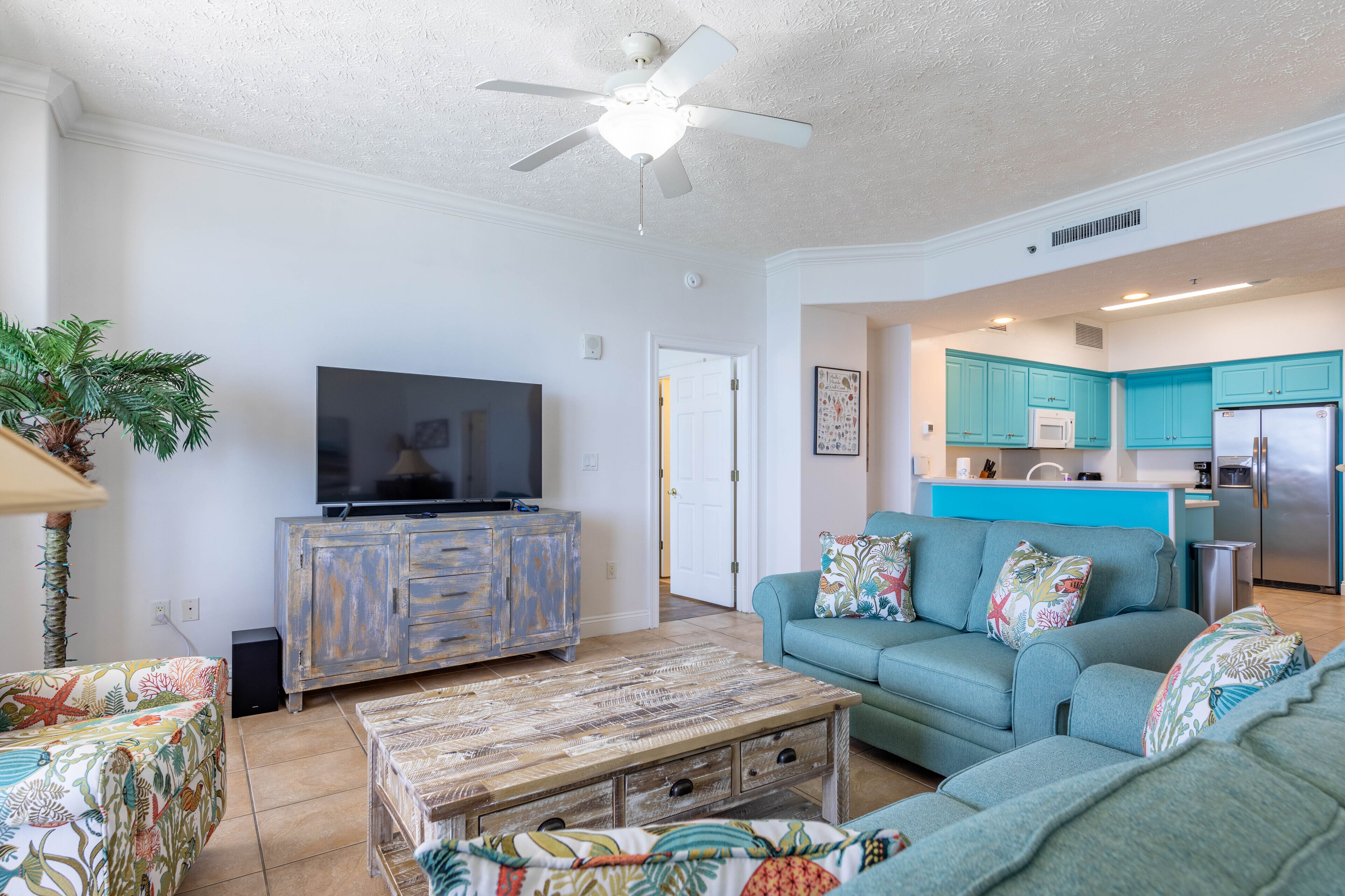 A living room with a television, a coffee table, and a sofa with colorful cushions.