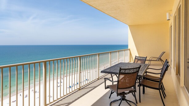 Un balcon avec une table et des chaises donnant sur une plage.