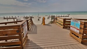 A wooden boardwalk leading to a beach with lounge chairs and umbrellas.