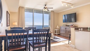 A modern hotel room with a dining area, a balcony with a view, a flat-screen TV, and a no-smoking sign.