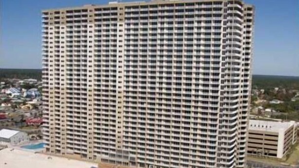 A high-rise hotel with multiple floors, a pool, and a beach view.