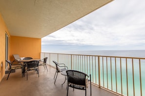 Enjoy the unobstructed ocean view from this balcony with a table and chairs.