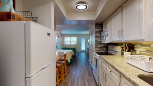 A kitchen with white cabinets, a granite countertop, and a microwave. - Studio Condo in Town, Near Beach, Shared Pool and Hot Tub (Port Aransas)