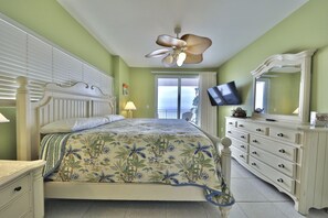 Un dormitorio con cama, cómoda, televisor y ventilador de techo.