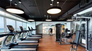 A gym with treadmills, weight machines, and a view of the ocean.