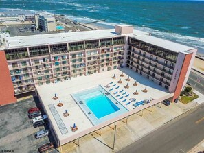 A hotel with a pool area, multiple balconies, and a view of the ocean.
