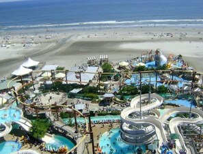 A water park with multiple slides and pools, surrounded by a beach and ocean views.