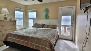 Un dormitorio con cama, cómoda y vista al mar por la ventana.