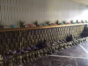 Stunning stone balustrade leads to a beautifully designed wall with lush greenery and elegant dark marble floors.
