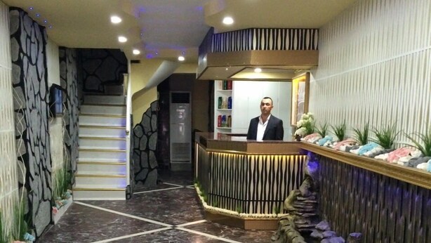 Zona de recepción con suelo de mármol, mostrador de recepción, escalera y pared con rayas verticales.