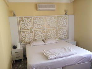 Cozy retreat with a neatly made bed, nightstand, and decorative headboard.