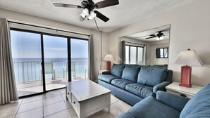 A modern hotel room with a balcony, a sofa, a coffee table, and a ceiling fan. - Summit 1 BR SLEEPS 5  ***BEACH CHAIRS INCLUDED*** (Panama City Beach)