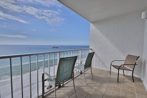 A balcony with two chairs and a view of the ocean.