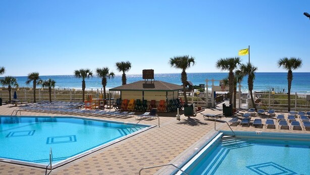 A pool area with two pools, lounge chairs, palm trees, and a beach view. - Summit 1 BR SLEEPS 5  ***BEACH CHAIRS INCLUDED*** (Panama City Beach)