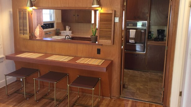 A kitchen with wooden cabinets, a built-in oven, and a countertop with stools.
