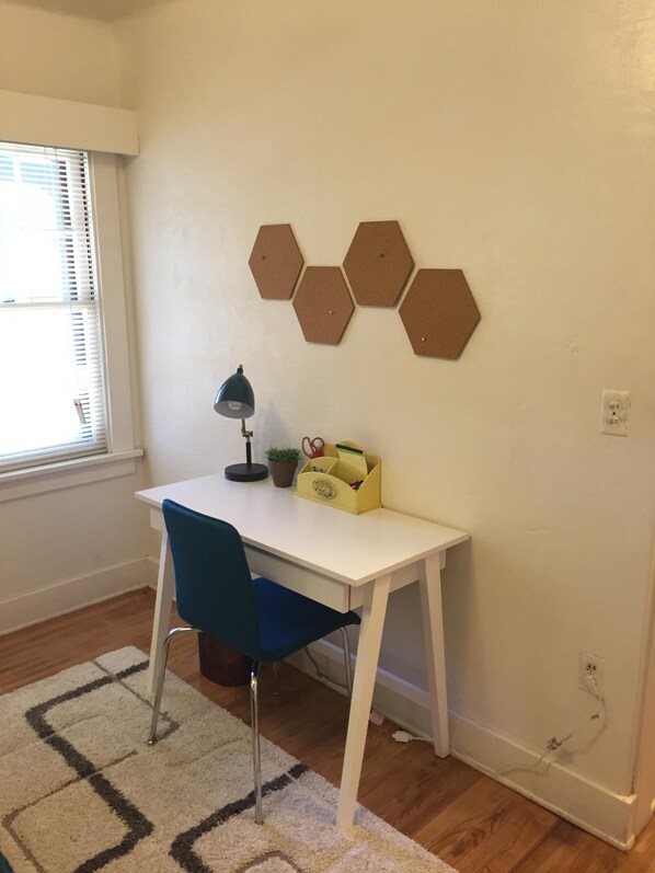 A small, neatly arranged room with a white desk, a blue chair, a desk lamp, and a hexagonal wall decoration. - Central Coast vacation rentals (Atascadero)