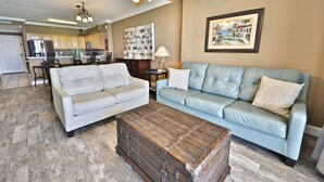 Ein Wohnzimmer mit einem hellblauen Sofa, einem weißen Sofa und einer Holzkistenkommode.