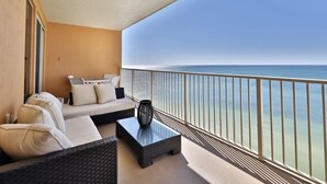 A balcony with a sofa, a coffee table, and a view of the ocean.