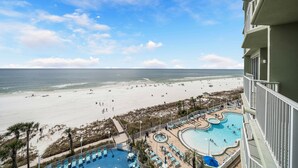 Un resort con zona de piscina, vista a la playa y un edificio con balcones.