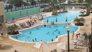 Un'ampia area piscina all'aperto con diverse piscine, lettini e ombrelloni.