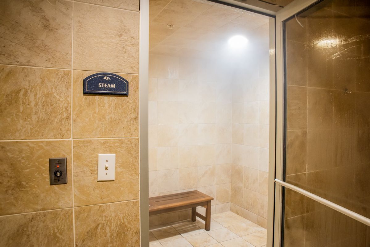 A steam shower with a bench, a control panel, and a sign labeled "STEAM".