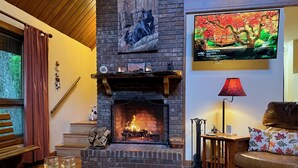 A cozy living room with a fireplace, a television mounted on the wall, and a comfortable seating area.