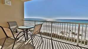 A balcony with a table and chairs overlooking a beach.