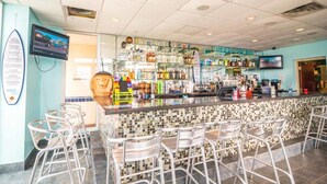 A bar area with a tiled backsplash, metal bar stools, and shelves stocked with various bottles.