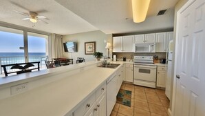 A spacious kitchen with white cabinets, a large island, and a view of the ocean.