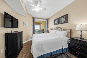 Una habitación de hotel con una cama, un escritorio, un televisor y un ventilador de techo.