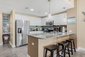 Una cocina moderna con una isla central, electrodomésticos de acero inoxidable y una lámpara colgante.