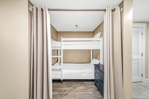 A bunk bed room with a wooden floor, a dresser, and beige curtains. - Grand Panama 5th Floor Gulf Front, Same Level As Walkover! (Panama City Beach)
