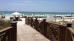 Un muelle de madera que conduce a sombrillas y sillas de playa.