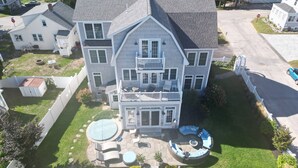 Una casa grande de dos pisos con un patio trasero amplio, que incluye un patio circular y una piscina.