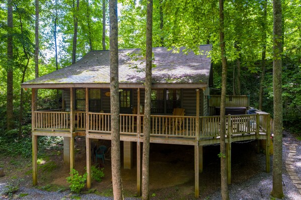 Situated in a forested area, this cabin offers a deck with a railing for outdoor relaxation.