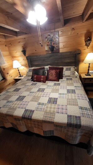 Cozy bedroom with a patchwork quilt-adorned bed and a painting above, offering a comfortable sleeping area.