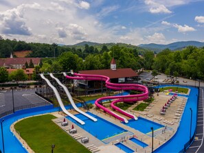 Enjoy a refreshing day at our water park with slides and a pool surrounded by lush greenery and hills.