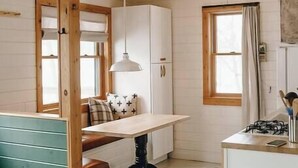 A compact kitchen with a wooden bench, a dining table, and a gas stove.