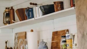 A kitchen with white cabinets, a coffee maker, a kettle, and a gas stove.